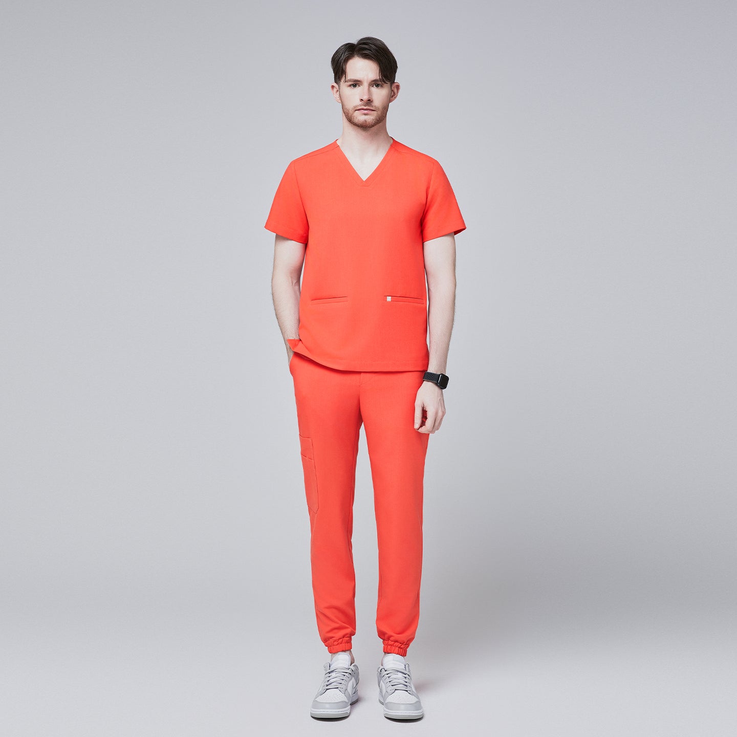 Man wearing tiger orange scrubs with a V-neck top and jogger-style pants, paired with white sneakers,Tiger Orange