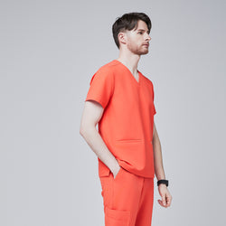 Image of Man wearing tiger orange scrubs with a V-neck and double pockets, looking to the side,Tiger Orange