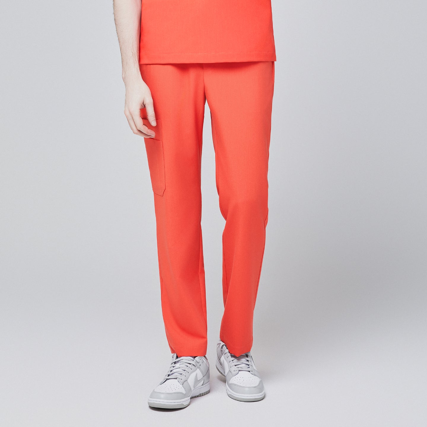 Front view of model wearing tiger orange scrub pants with a single side pocket, paired with white sneakers, set against a light gray background,Tiger Orange