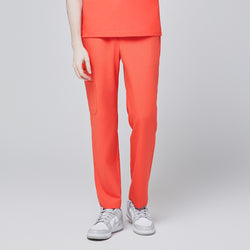 Image of Front view of model wearing tiger orange scrub pants with a single side pocket, paired with white sneakers, set against a light gray background,Tiger Orange