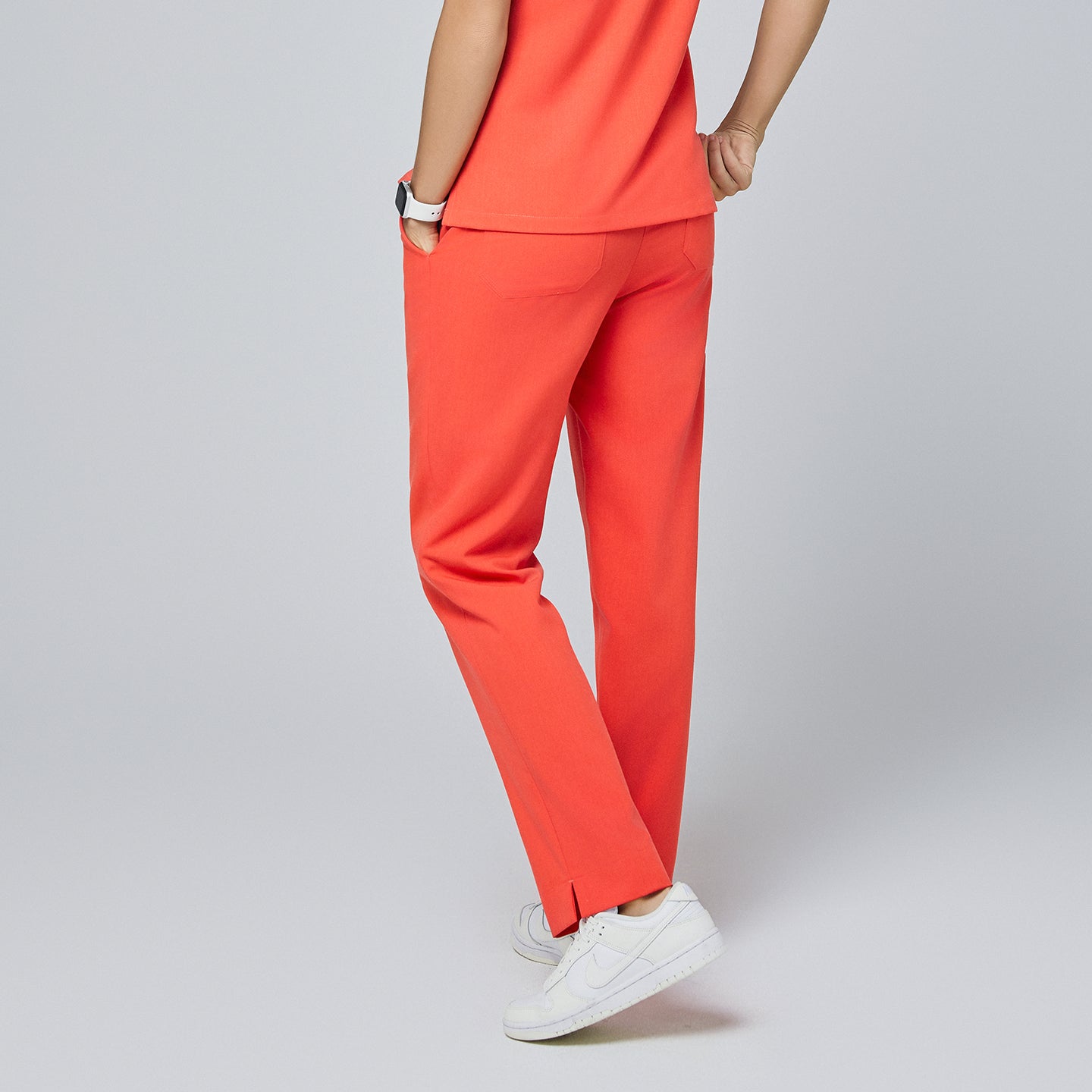 Back view of tiger orange straight-leg scrub pants with a split hem, featuring rear pockets and paired with white sneakers,Tiger Orange