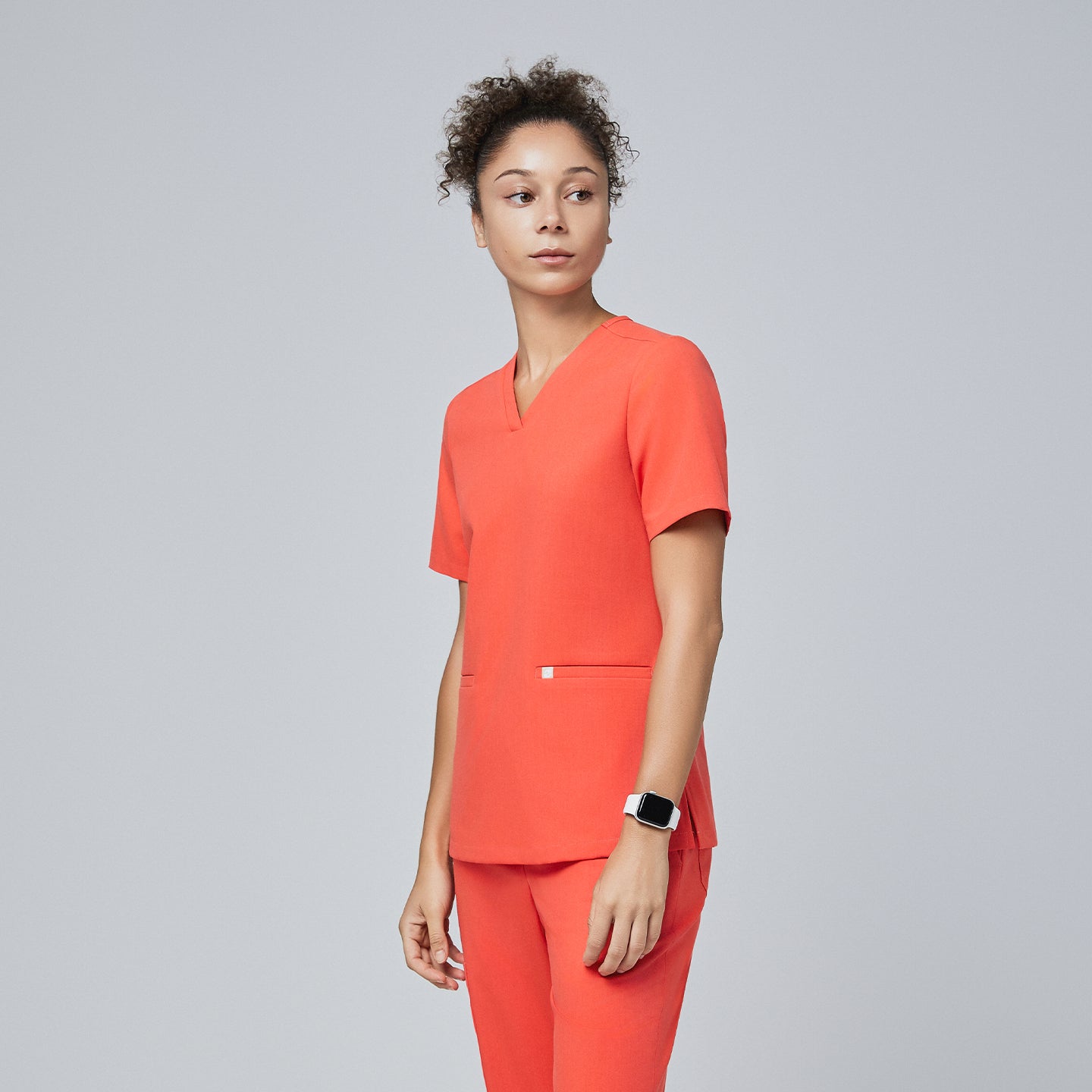 A woman wearing a Tiger Orange Double Pocket Scrub Top and Tiger Orange Straight Split Hem Scrub Pants,Tiger Orange