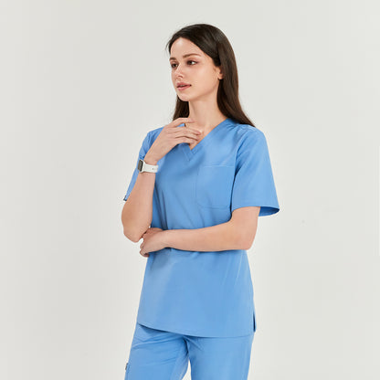  Woman wearing a V-neck scrub top and matching pants, standing with one hand touching her neck, looking to the side,Ceil Blue