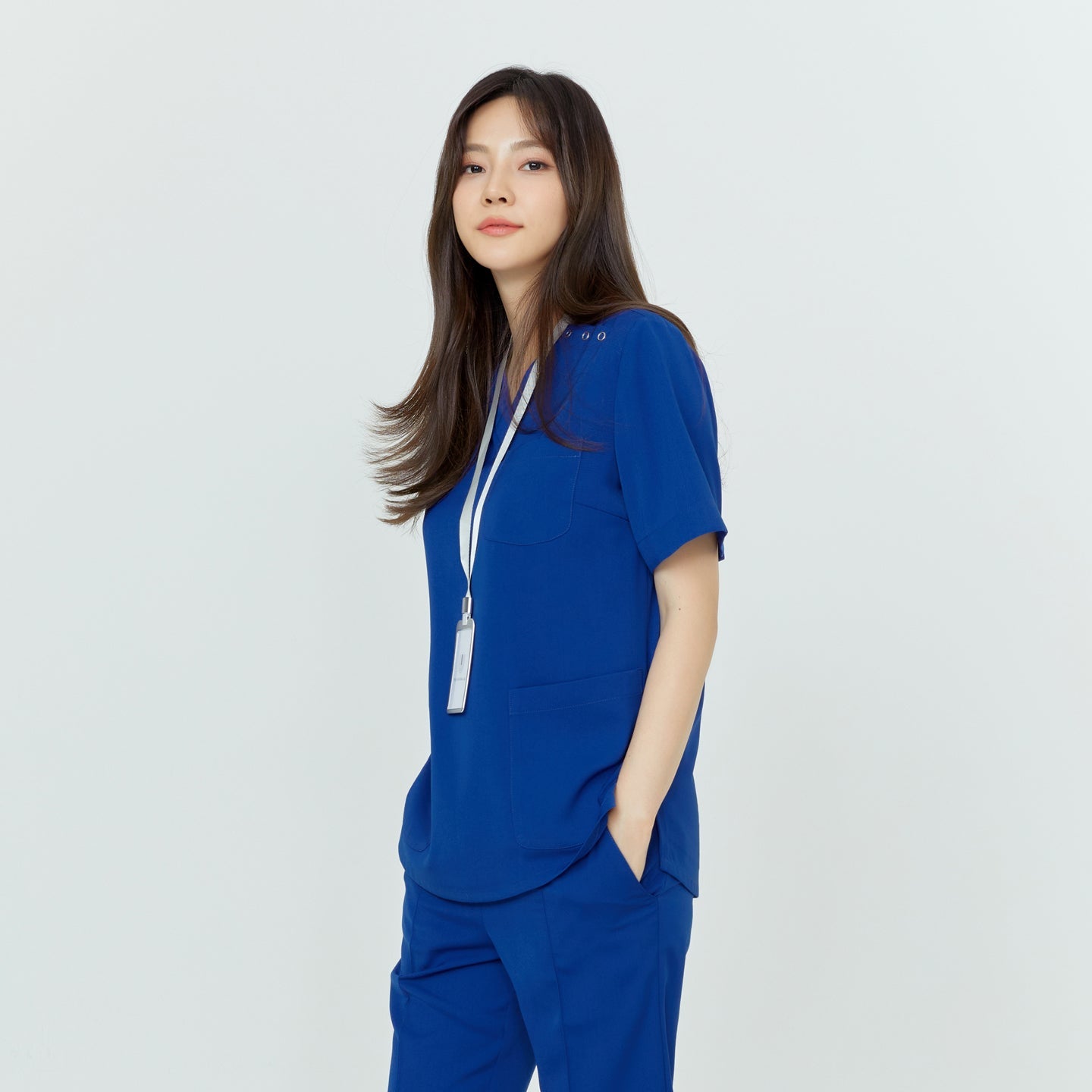 Woman in medical scrubs looking to the side with hands in pockets,Royal Blue