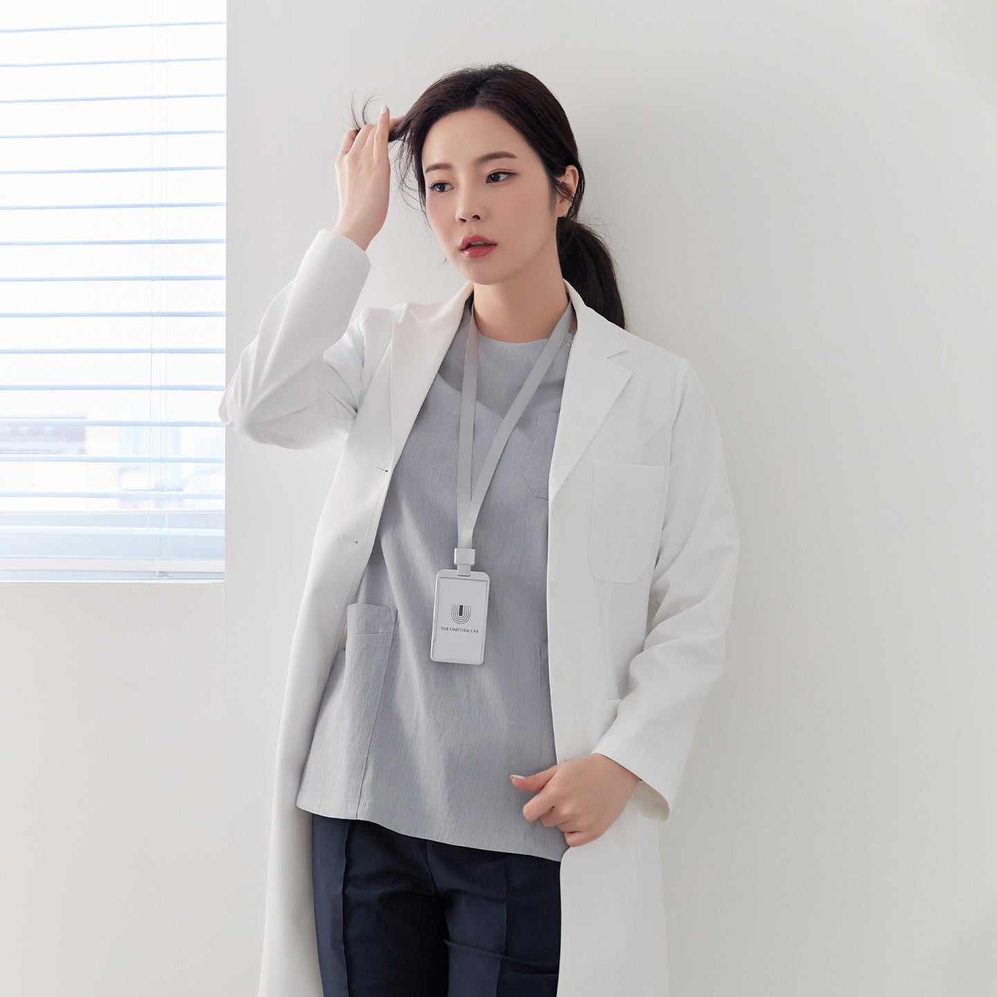 Woman wearing Zenir White Long Lab Coat LCW-04, standing in front of a window,White
