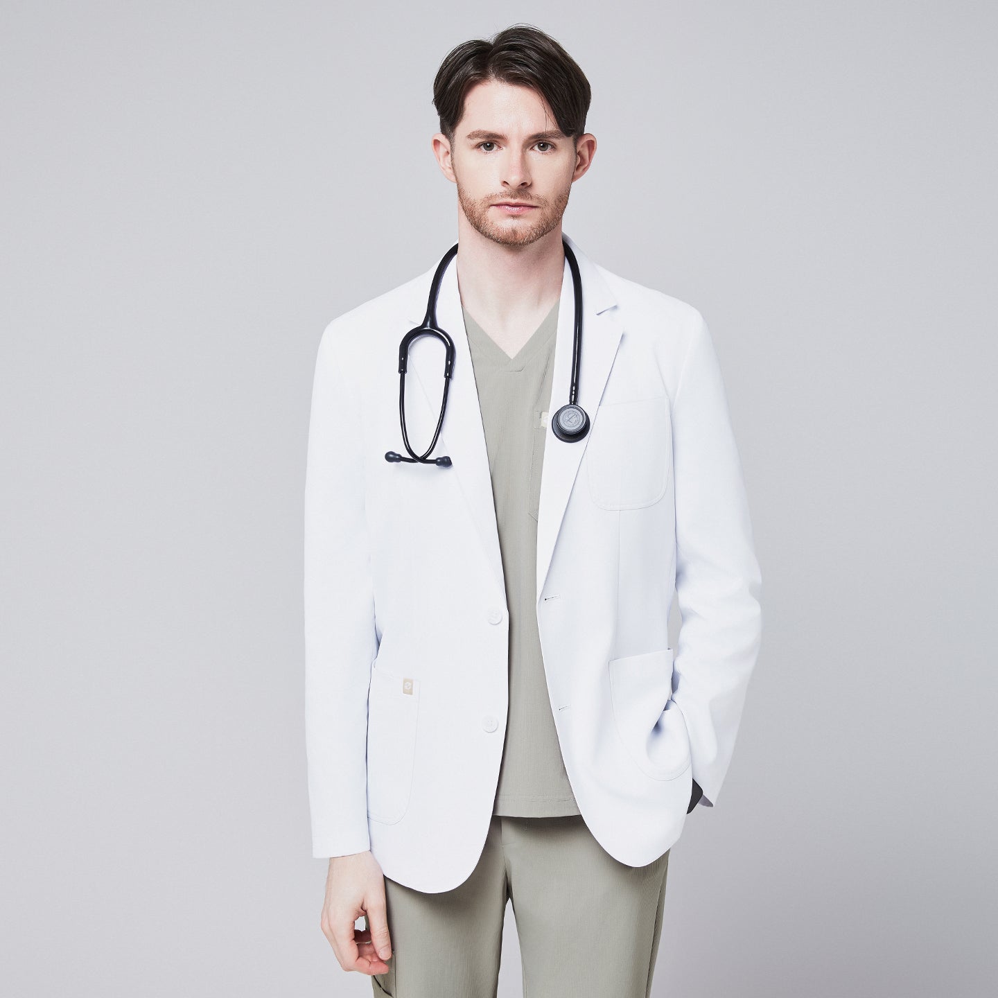 Front view of a male model wearing a white short lab coat over olive green scrub pants, showcasing clean and tailored design,White