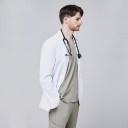 Image of Side view of a male model wearing a white short lab coat over olive green scrub pants, showcasing clean and tailored design,White