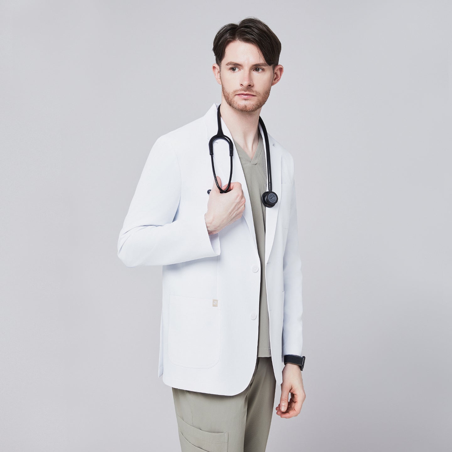 Front view of a male model wearing a white short lab coat over olive green scrub pants, showcasing clean and tailored design,White