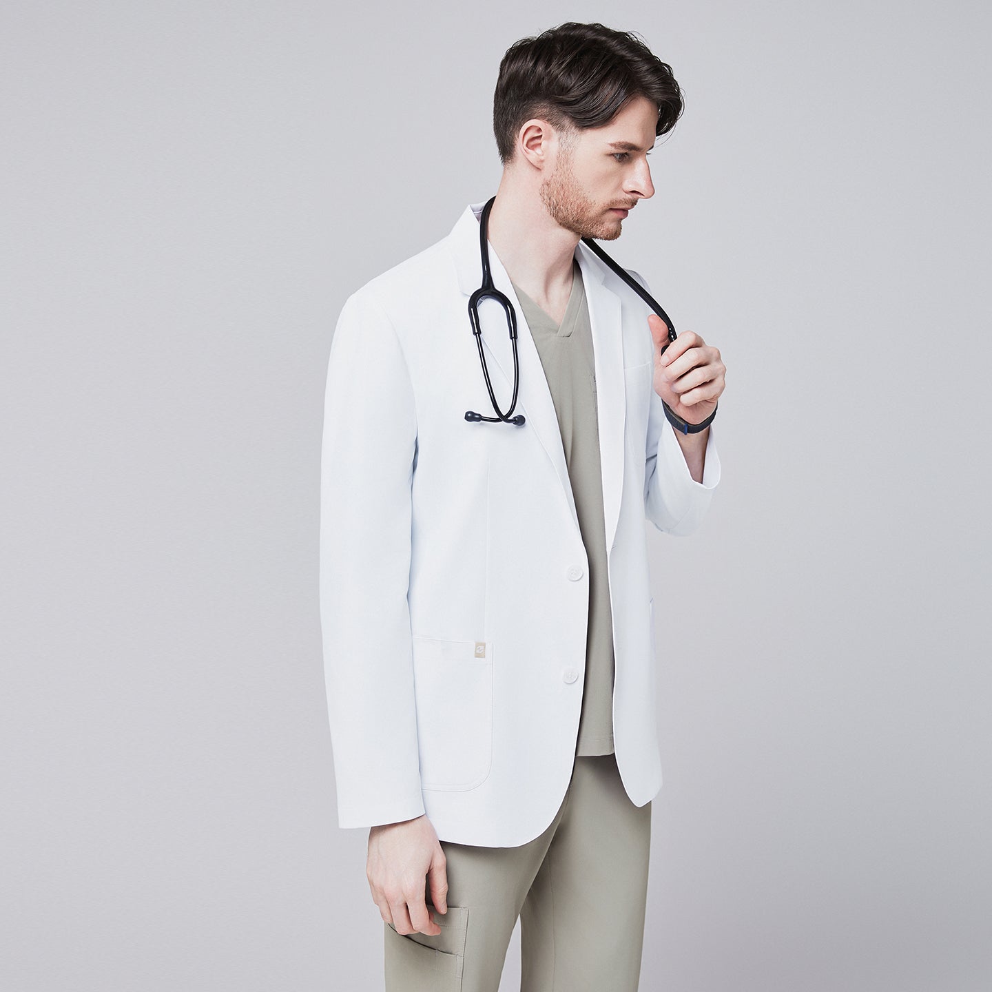 Front view of a male model wearing a white short lab coat over olive green scrub pants, showcasing clean and tailored design,White