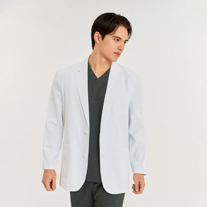A man wearing a white short lab coat over a charcoal gray scrub top, looking to the side with a neutral expression,White