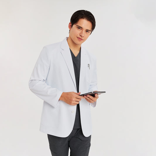 A man wearing a white short lab coat over a charcoal gray scrub top and pants, holding a tablet,White