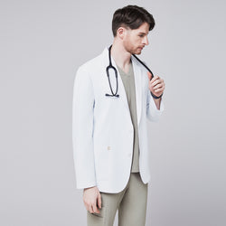 Image of Male model wearing a white short lab coat over an olive green scrub set, holding a stethoscope in a side pose,White