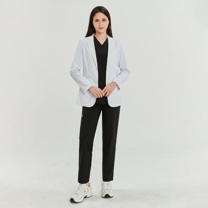 Full-body shot of a model wearing a white lab coat over a black scrub top and black pants, paired with white sneakers. The model is standing straight, facing forward,White