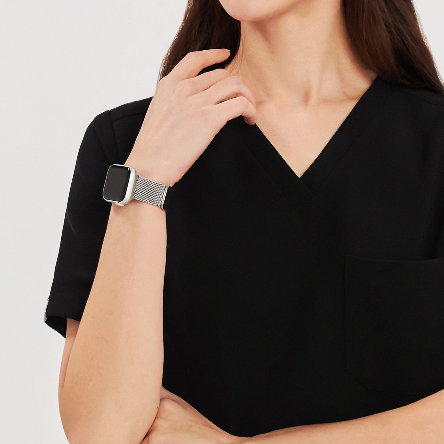 Close-up of a woman wearing a black soft stretch scrub top, showing the V-neck and chest pocket details, with a smartwatch on her wrist,Black