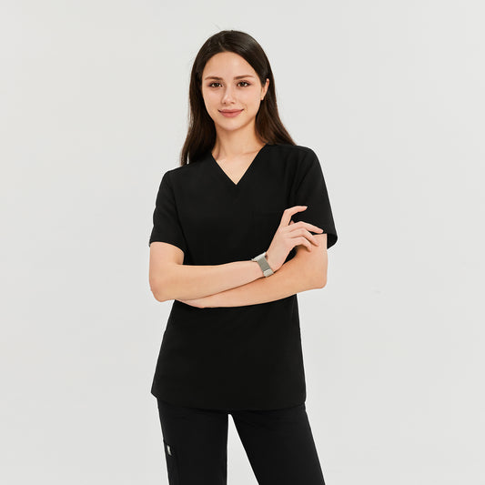 Woman wearing a black soft stretch scrub top and matching pants, standing with arms crossed and smiling,Black