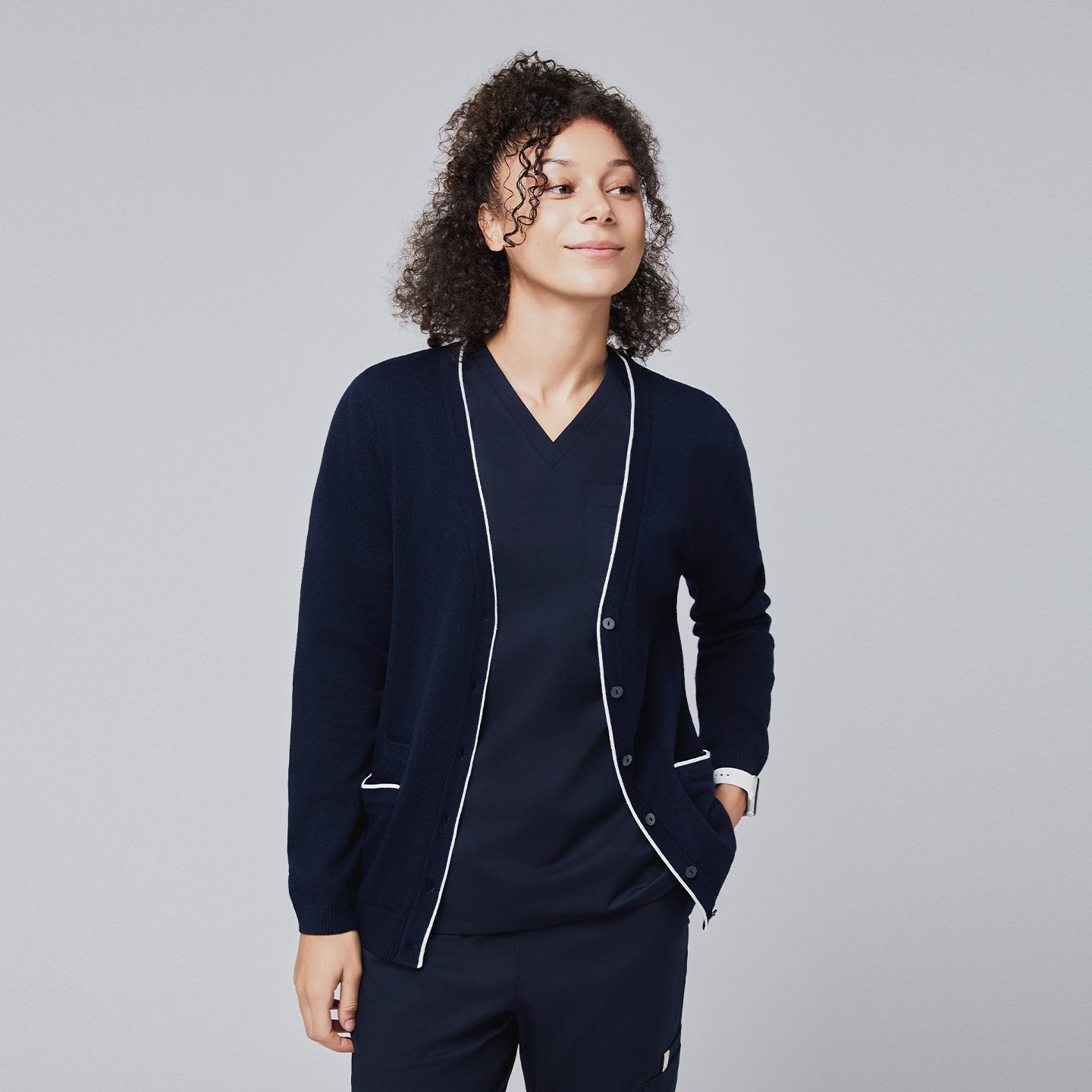 Woman wearing a navy scrub set layered with a coordinating cardigan featuring white trim, exuding a relaxed and professional vibe,Navy