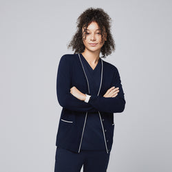 Image of Confident woman wearing a navy scrub set paired with a navy cardigan featuring white trim, standing with arms crossed,Navy